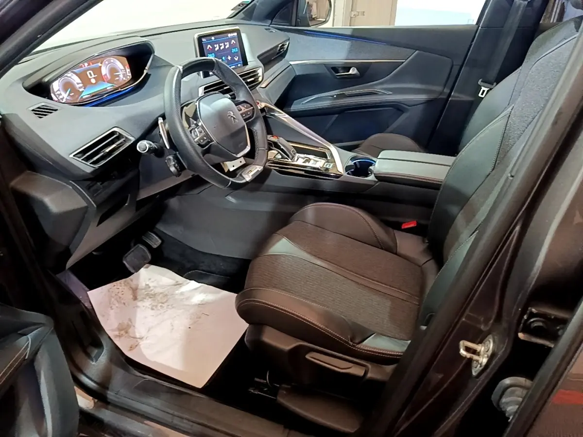 Intérieur avant droit du Peugeot 3008 gris foncé, volant cuir multifonctions et tableau de bord numérique lumineux.
