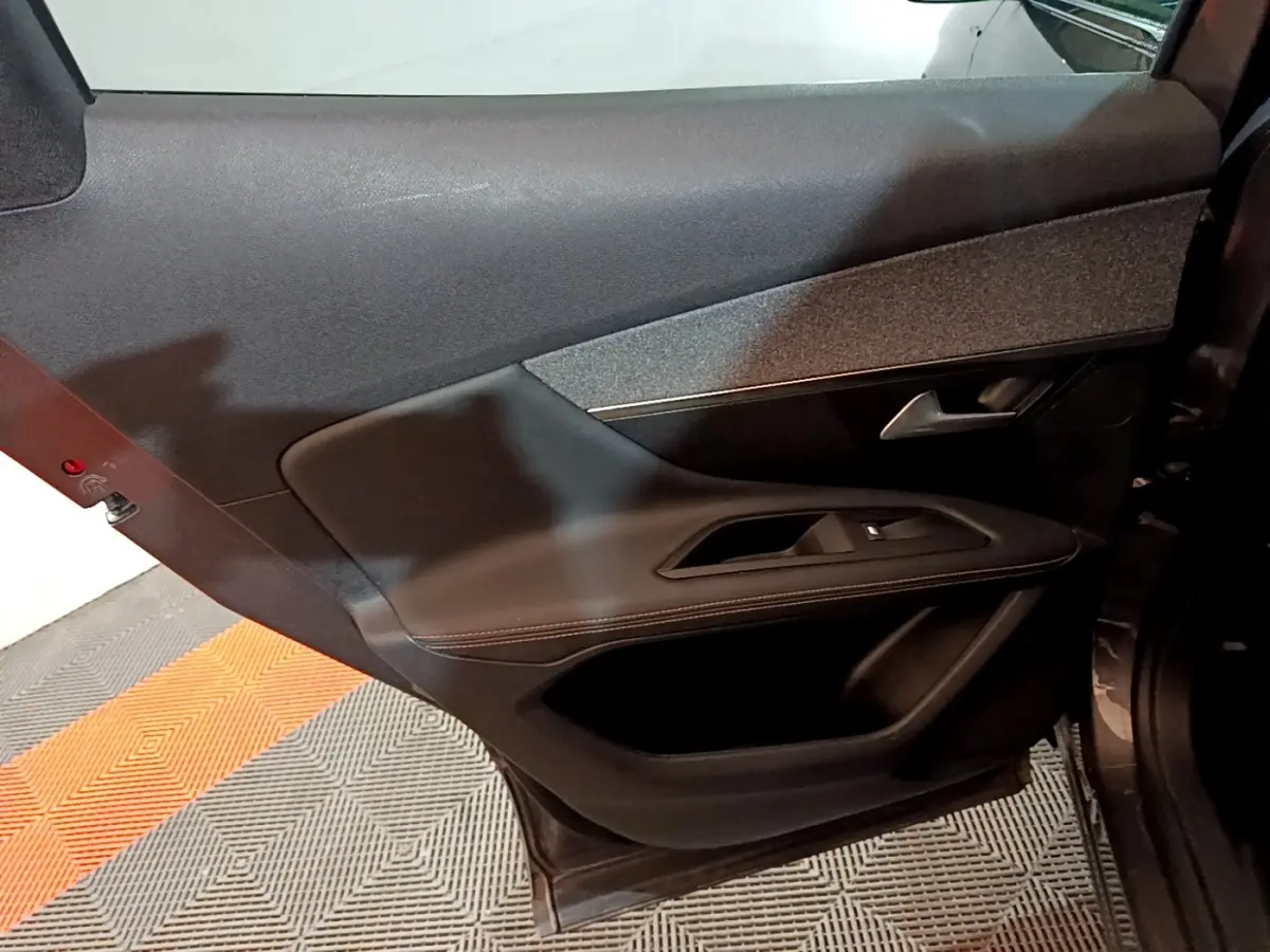 Porte arrière droite ouverte d’un Peugeot 3008 gris foncé, avec garniture intérieure noire et commande de vitre.