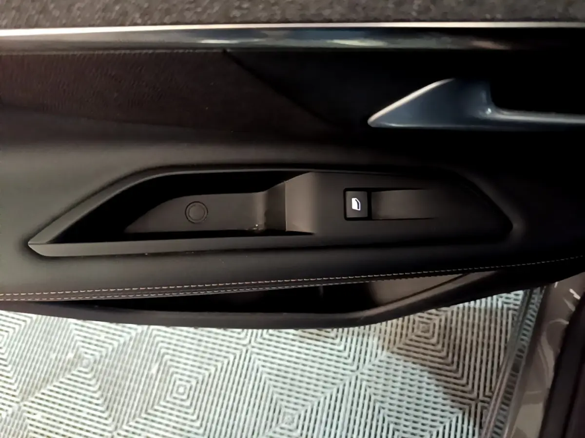 Gros plan sur la poignée intérieure de porte côté gauche en cuir noir avec surpiqûres contrastantes du Peugeot 3008 gris foncé.