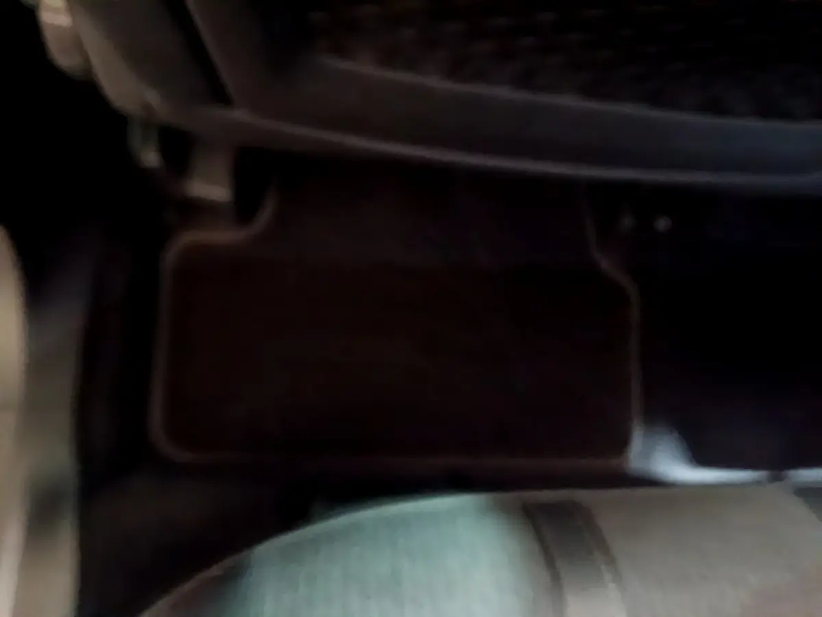 Détail du tapis de sol et partie inférieure du siège avant dans l’habitacle sombre d’un Peugeot 3008 gris foncé.