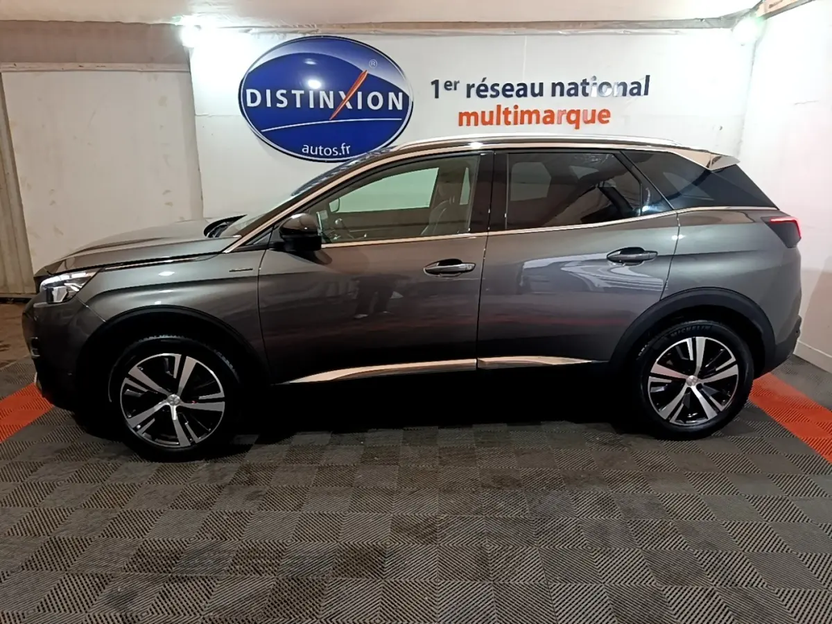 Vue de profil côté gauche d’un Peugeot 3008 gris foncé GT Line dans un showroom avec logo Distinxion en arrière-plan.