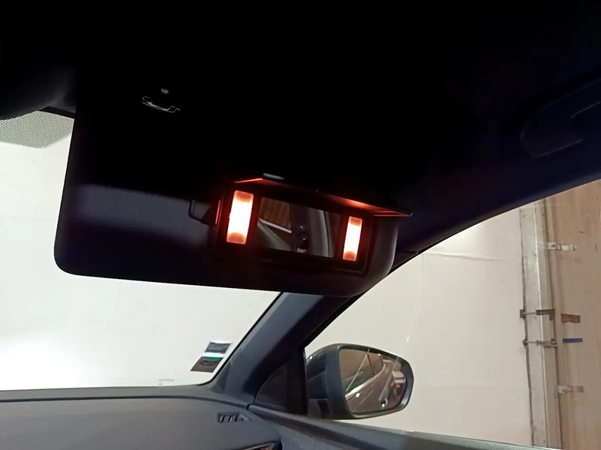 Détail du miroir de courtoisie éclairé sur le pare-soleil côté conducteur d’un Peugeot 3008 gris foncé.