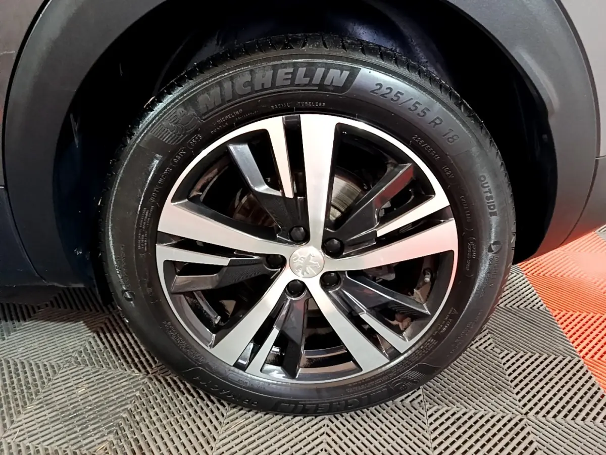 Gros plan sur la roue avant droite du Peugeot 3008 gris foncé, jante alliage bicolore et pneu Michelin visible.