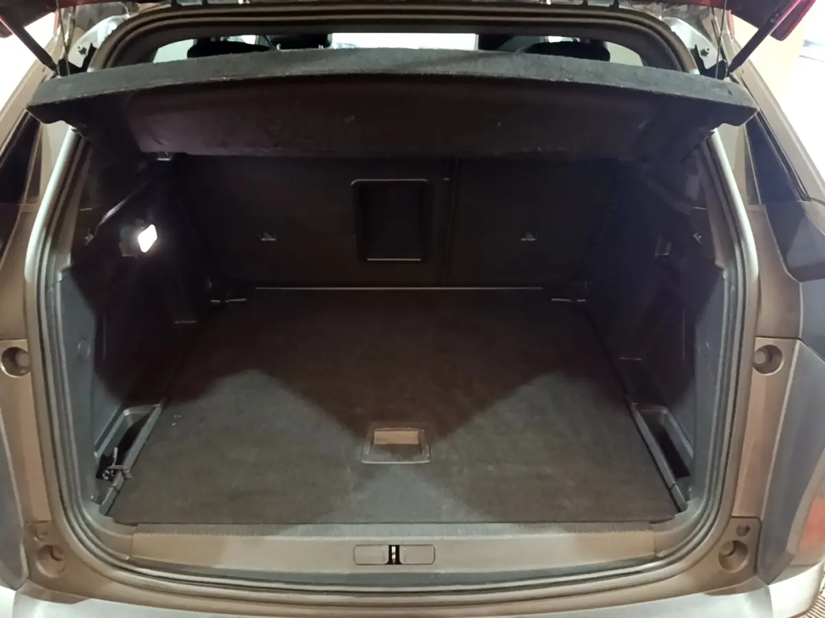Coffre ouvert vu de l'arrière d'un Peugeot 3008 gris foncé, avec plancher plat et banquette rabattue partiellement.