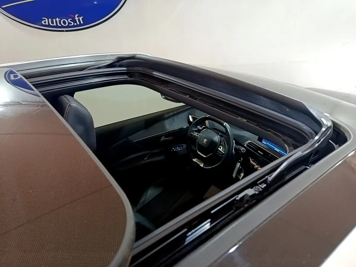 Vue plongeante sur l'intérieur du Peugeot 3008 gris foncé, mettant en valeur le volant cuir multifonctions et le tableau de bord digital.