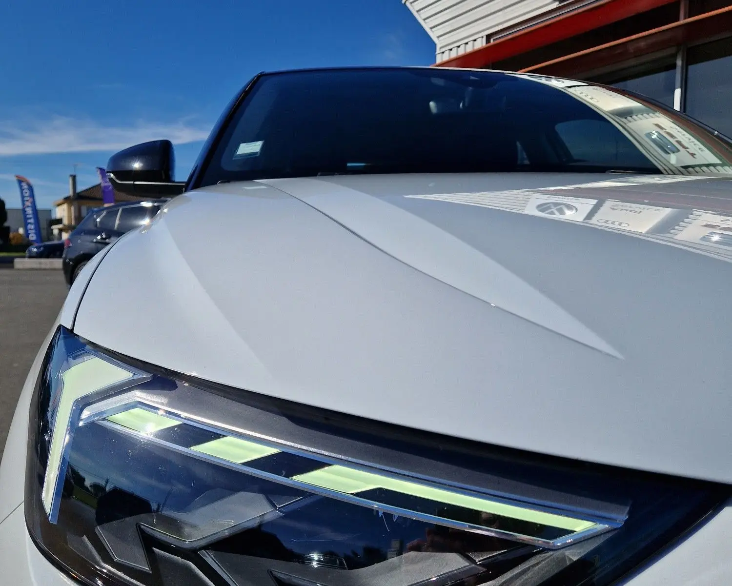 Gros plan sur le phare avant gauche de l'Audi A1 Sportback blanc glacier, soulignant ses LED distinctives et lignes anguleuses.