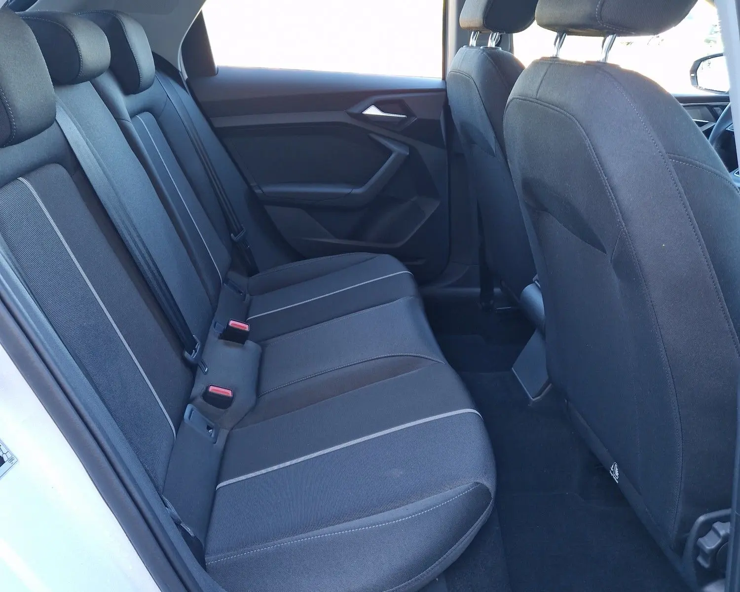 Vue intérieure côté gauche montrant les sièges arrière noirs d'une Audi A1 Sportback blanc glacier 2020.