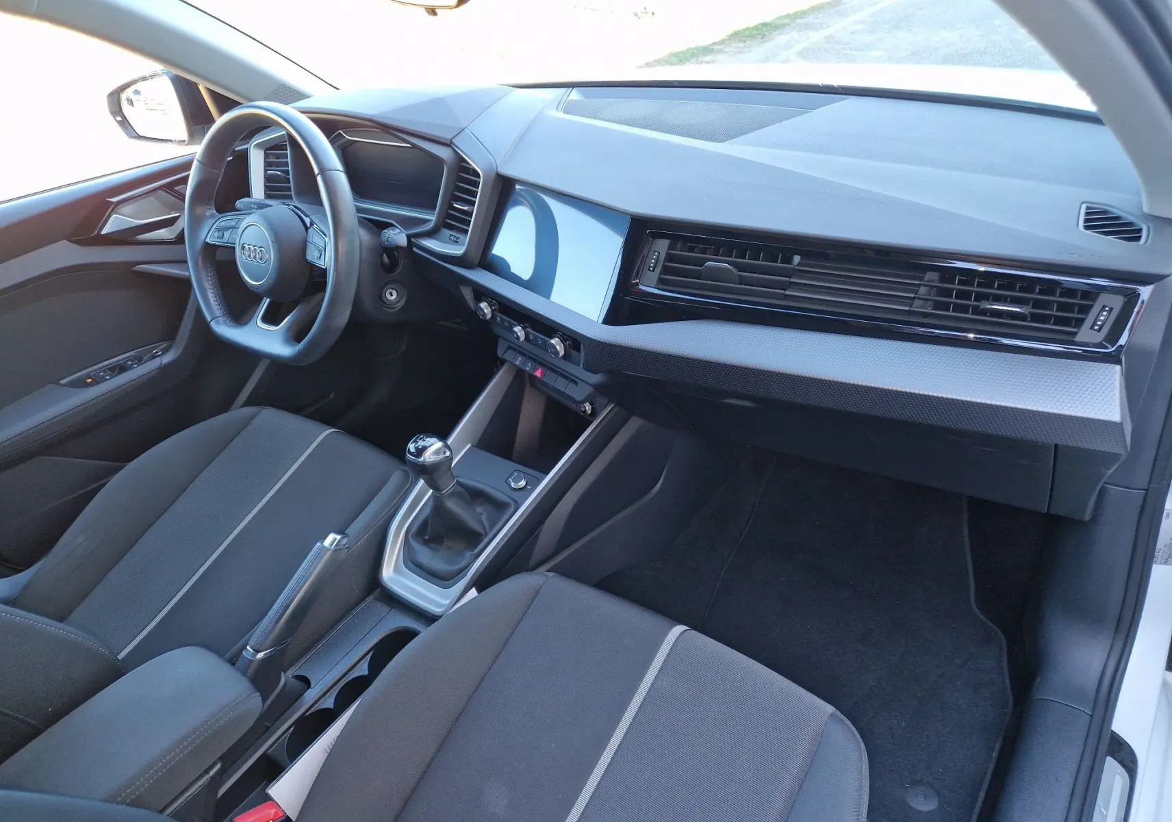 Intérieur de l'Audi A1 Sportback 25 TFSI 2020 vu côté passager, tableau de bord moderne et boîte manuelle noire.