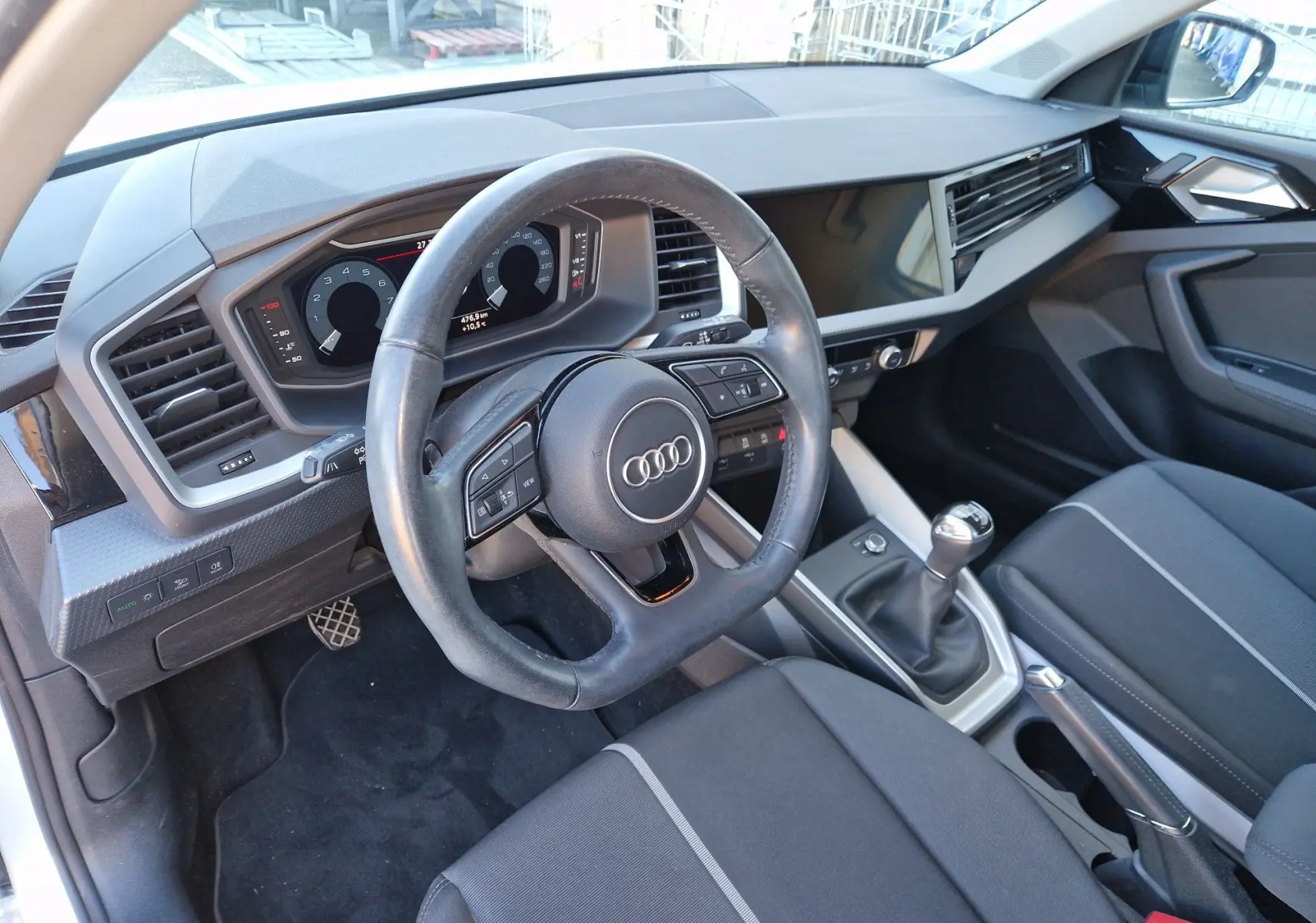 Vue intérieure côté conducteur de l'Audi A1 Sportback 25 TFSI 2020, volant cuir, tableau de bord numérique et boîte manuelle.