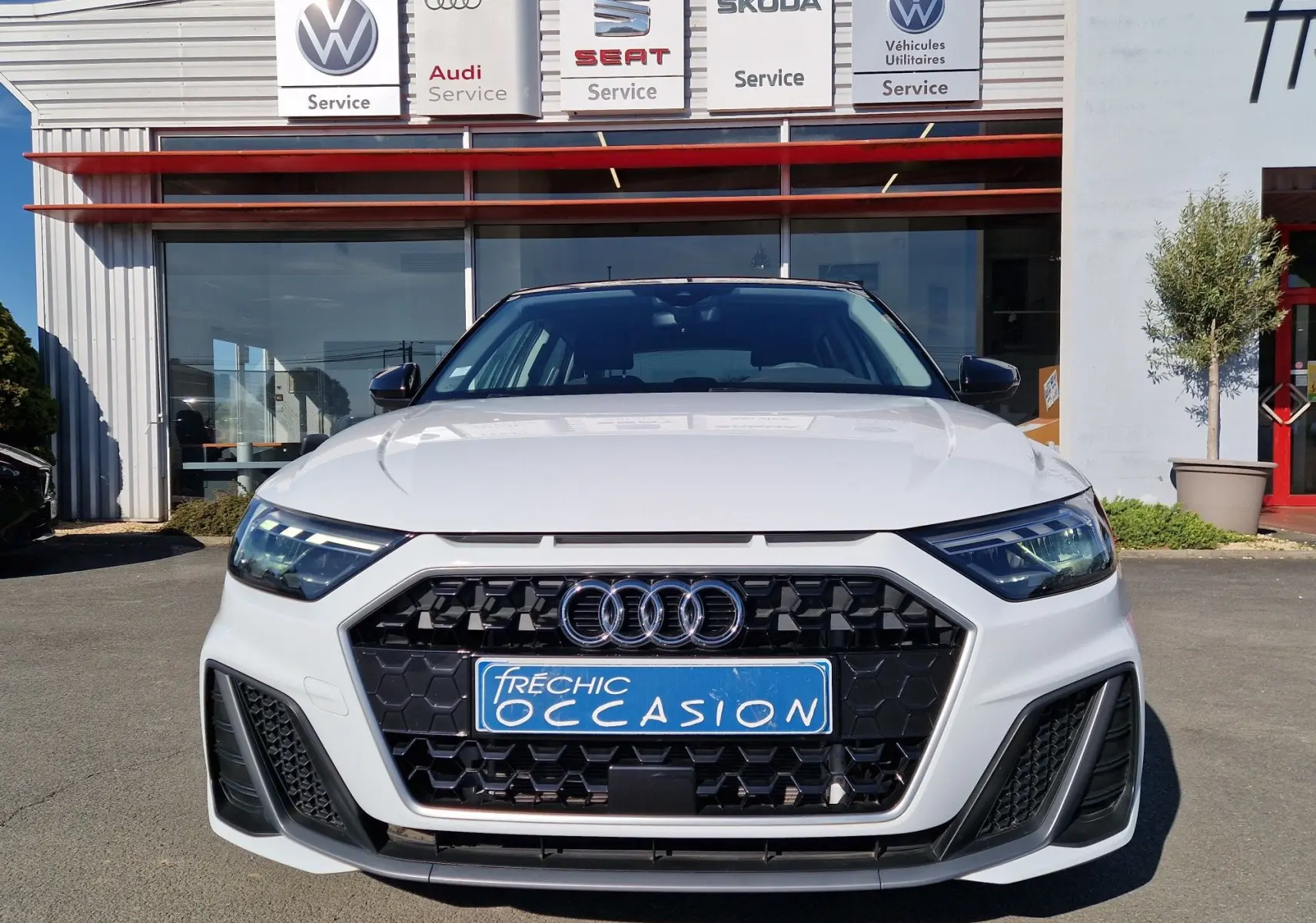 Vue frontale d'une Audi A1 Sportback blanc glacier 2020 avec calandre noire hexagonale et phares LED.
