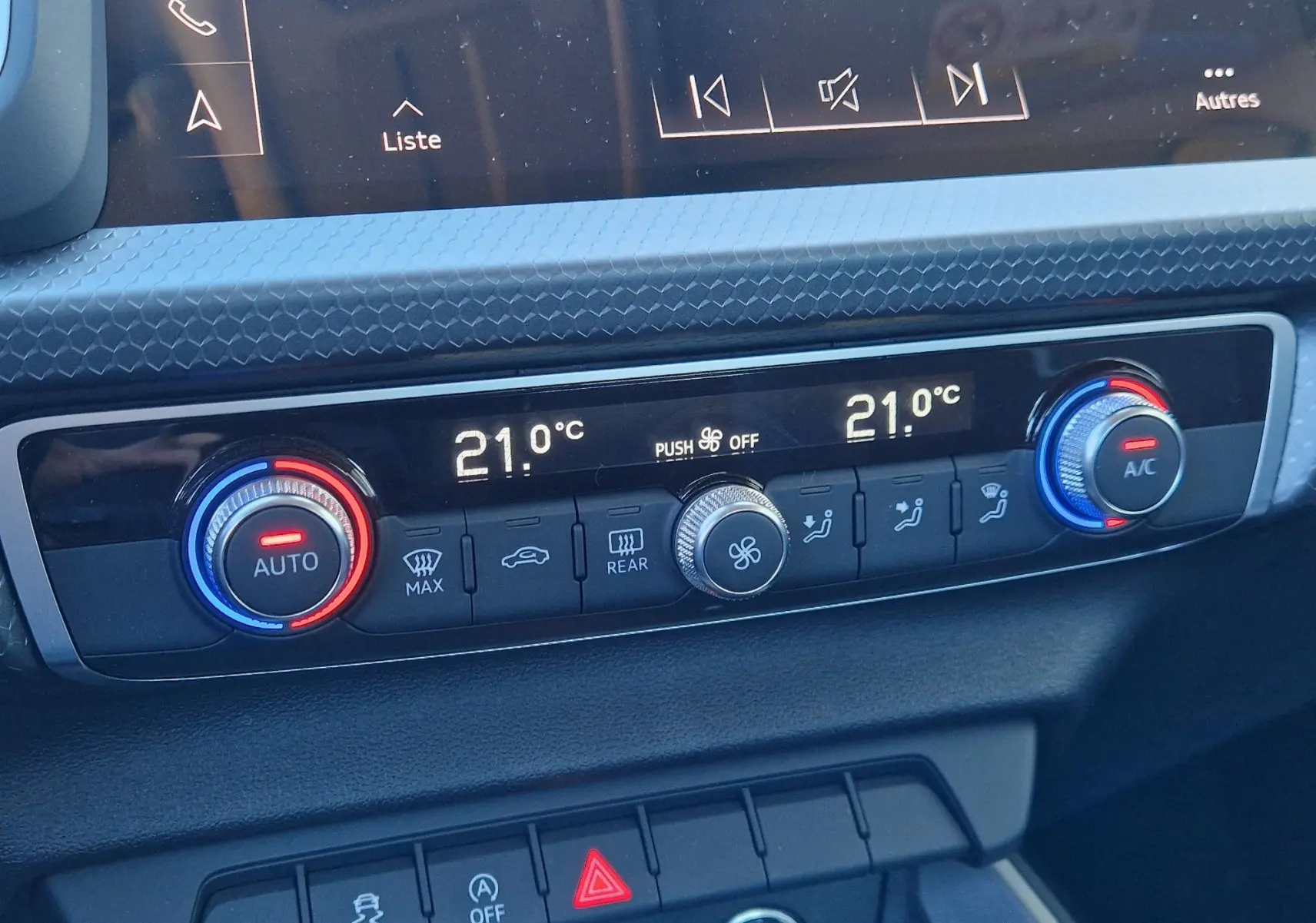 Gros plan sur la commande de la climatisation automatique de l'Audi A1 Sportback blanc glacier, affichant 21°C des deux côtés.