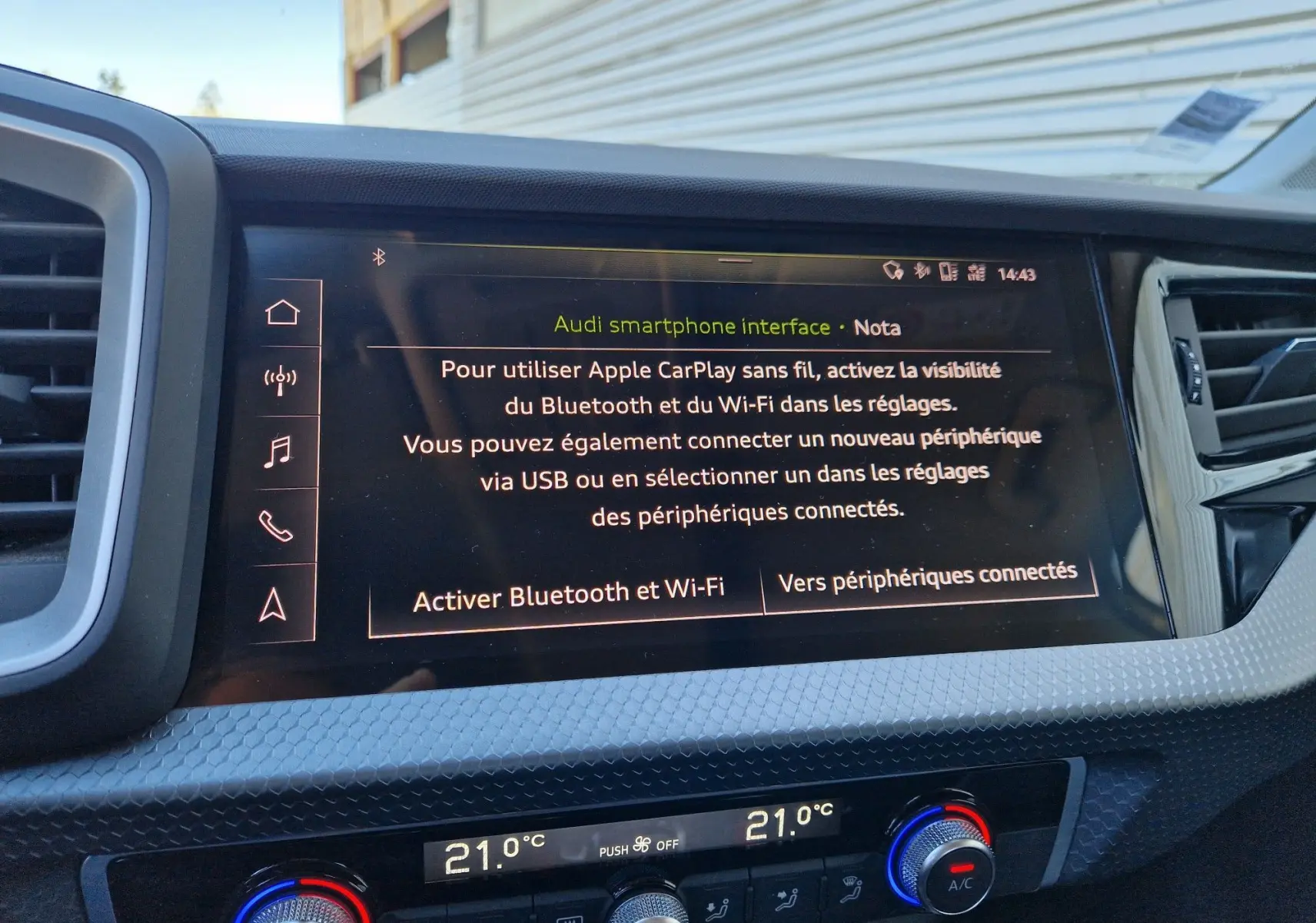 Écran central tactile de l’Audi A1 Sportback 25 TFSI blanc glacier, affichant l’interface smartphone avec commandes climatisation en dessous.