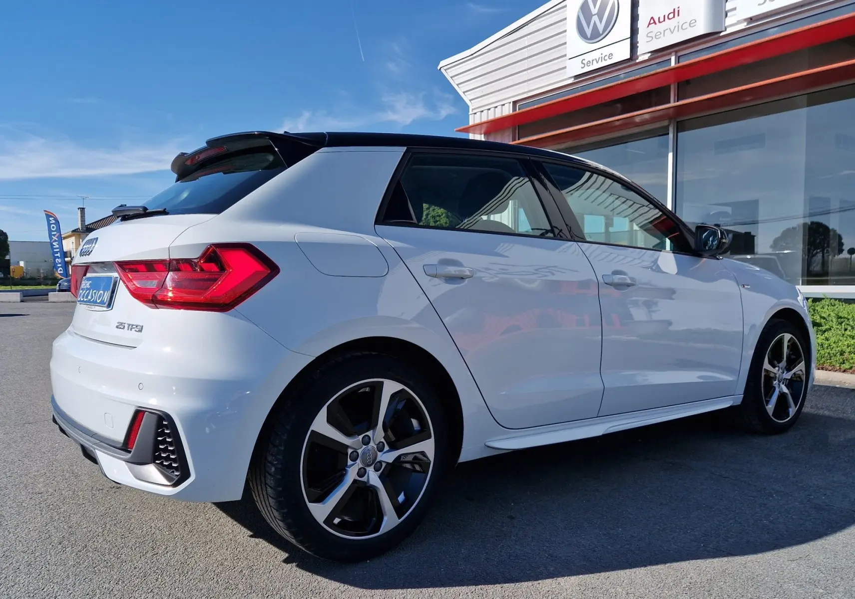 Vue 3/4 arrière droite d'une Audi A1 Sportback blanc glacier avec toit noir et jantes alliage distinctives.