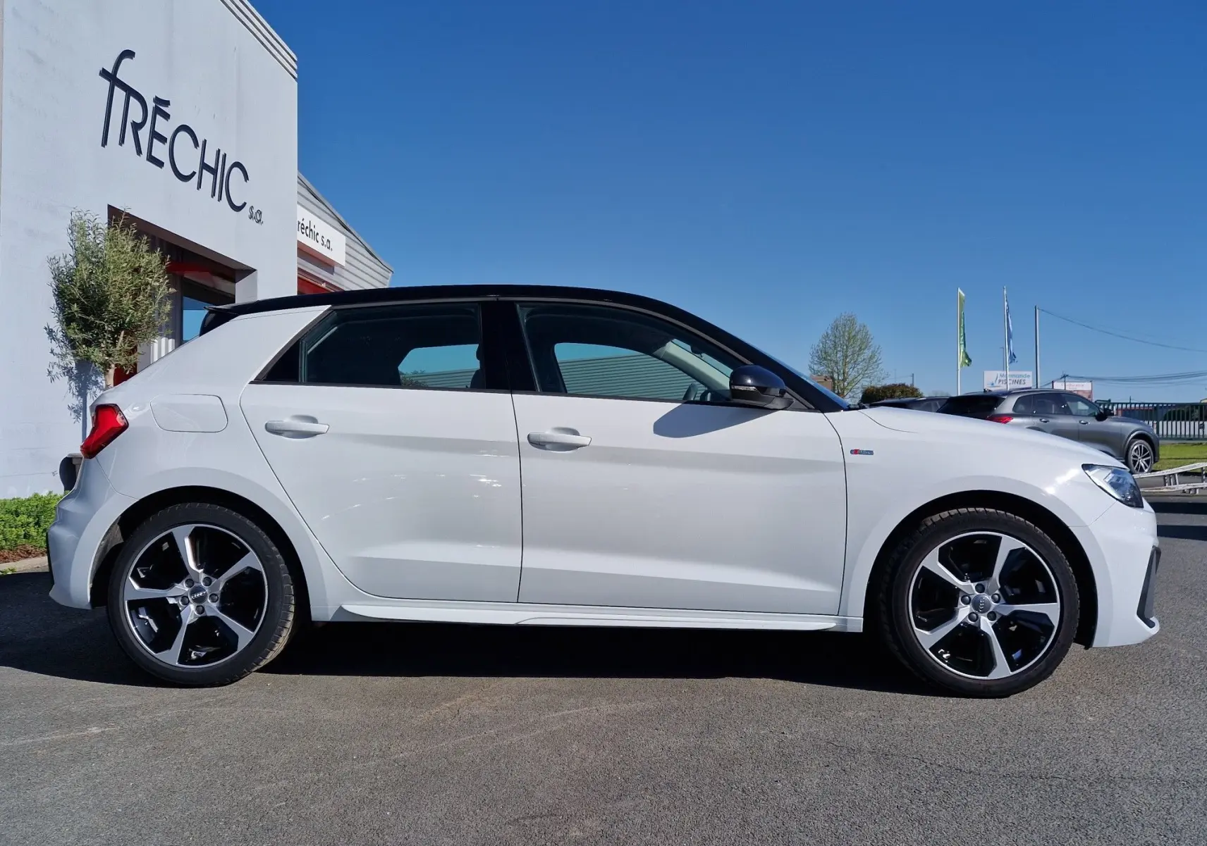 Audi A1 Sportback blanc glacier vue de profil côté gauche, avec toit noir et jantes alliage noires distinctives.