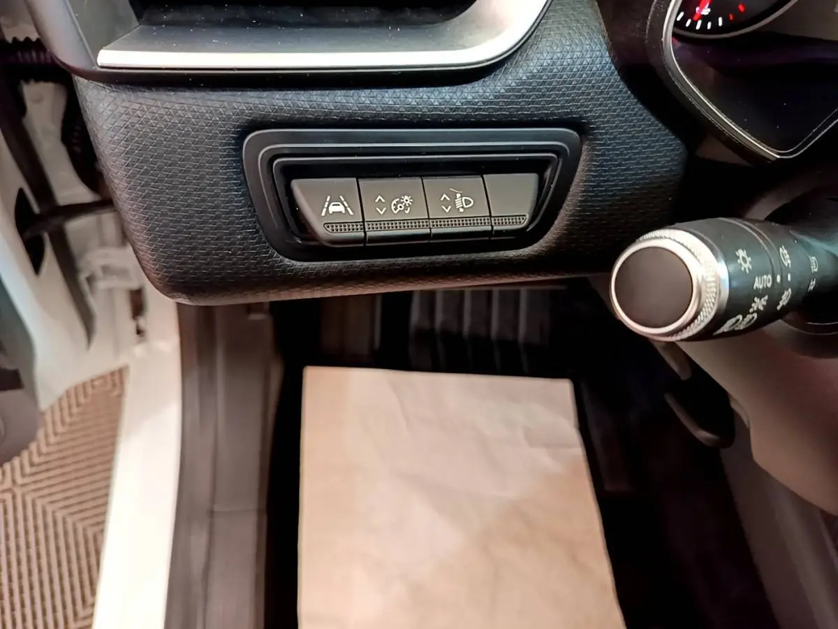 Vue intérieure côté conducteur de la Renault Clio Business Blue dCi 85 blanche, avec commandes d'assistance et éclairage au tableau de bord.