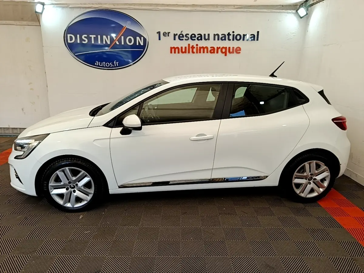 Profil droit d'une Renault Clio Business Blue dCi 85 blanche, en intérieur avec jantes alliage et rétroviseurs blancs.