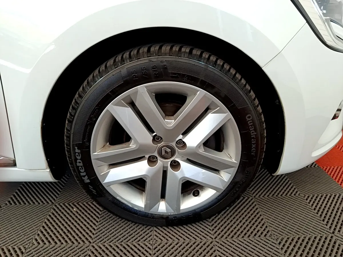 Gros plan sur la roue avant droite d'une Renault Clio Business Blue dCi 85 blanche avec jante alliage siglée Renault.