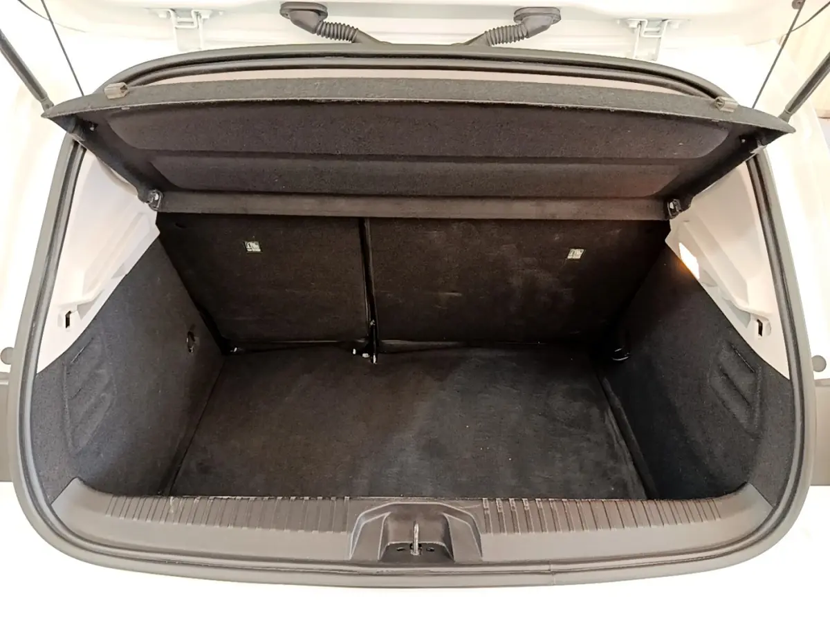 Coffre ouvert vu de face d’une Renault Clio Business Blue dCi 85 blanche, intérieur noir et espace de rangement visible.