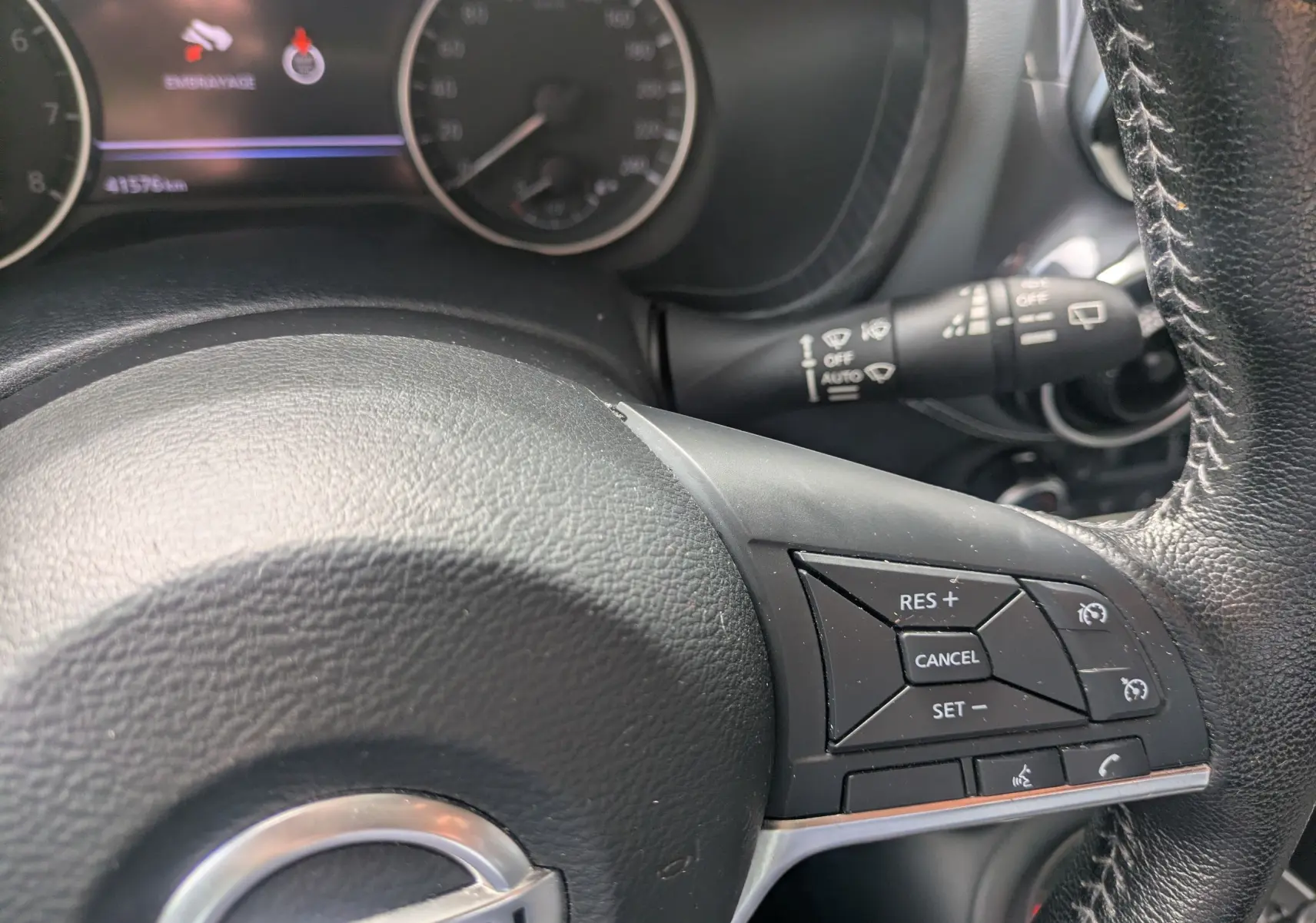Vue rapprochée du volant noir du Nissan Juke rouge 2020, avec commandes de régulateur de vitesse visibles.