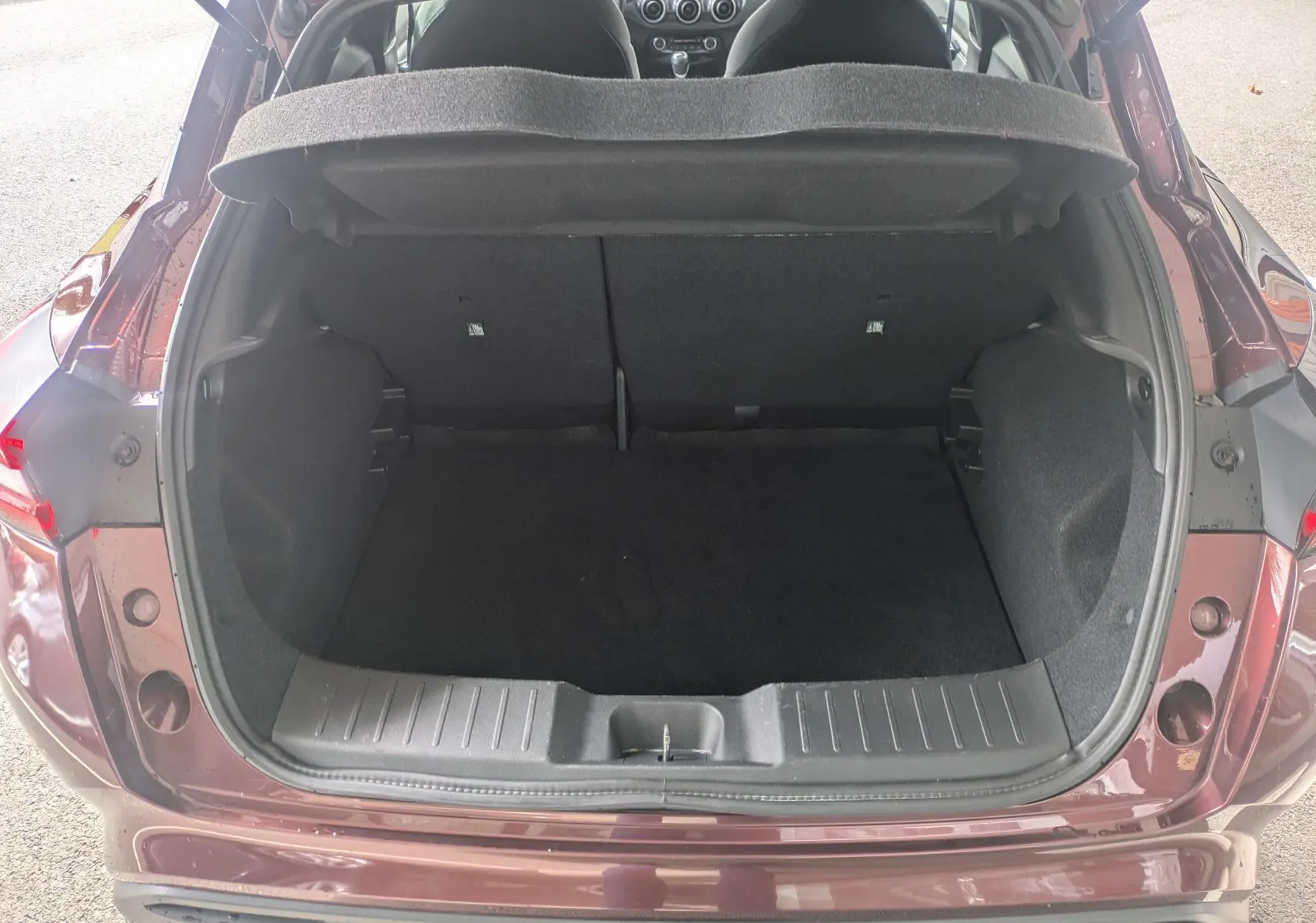 Coffre ouvert vu de l'arrière d'un Nissan Juke rouge 2020, montrant l'espace de chargement et l'intérieur sombre.