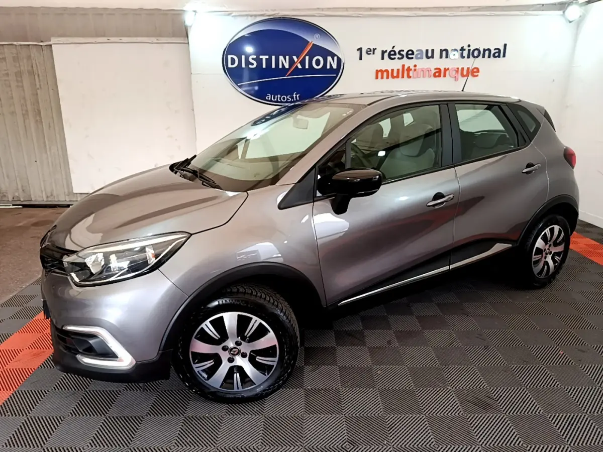 Renault Captur Business gris foncé vu de profil côté gauche dans un showroom avec logo Distinxion en arrière-plan.