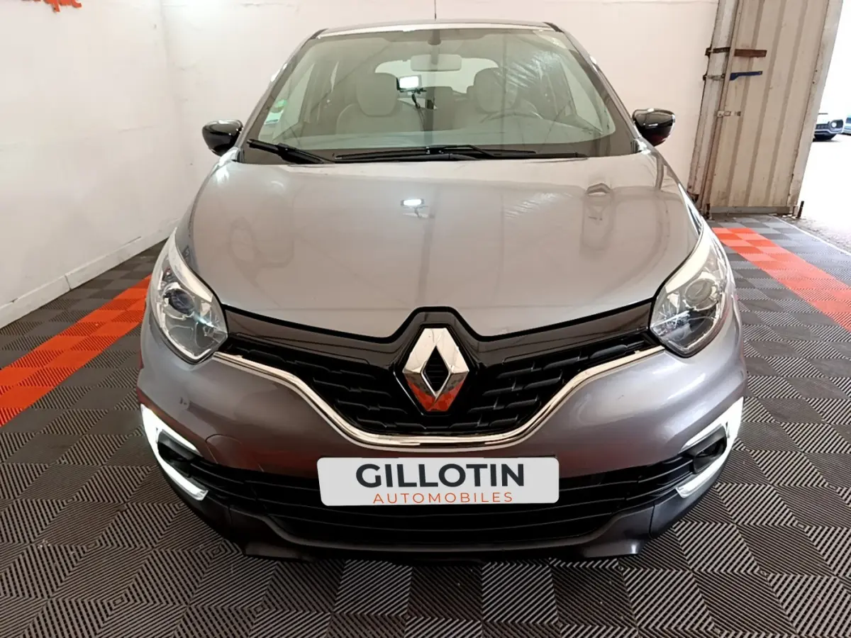Vue avant d'une Renault Captur Business gris foncé avec phares LED et calandre noire brillante dans un garage.