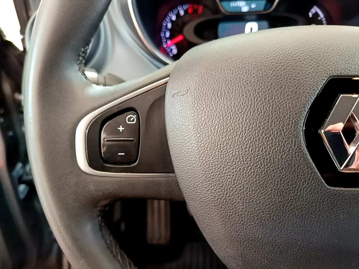 Gros plan sur le volant cuir gris foncé du Renault Captur Business, avec commandes de régulateur de vitesse à gauche.