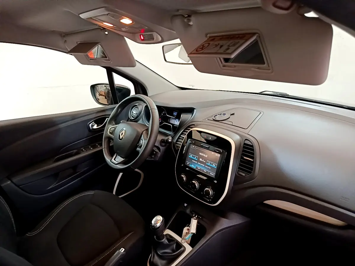 Vue intérieure côté conducteur du Renault Captur Business gris foncé, avec volant cuir, écran tactile 7 pouces et levier de vitesse manuel.