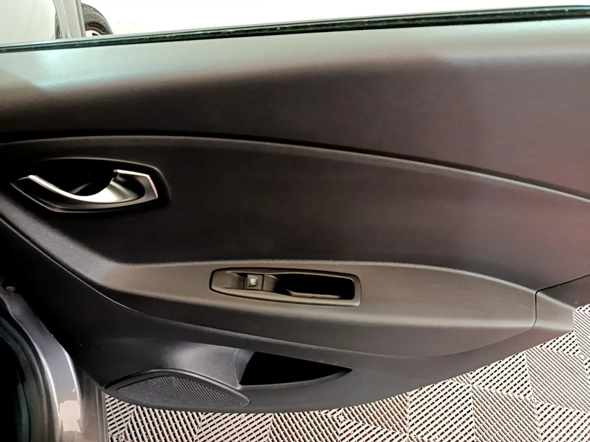 Vue intérieure côté gauche de la porte d'une Renault Captur gris foncé, avec poignée argentée et commande de vitre.