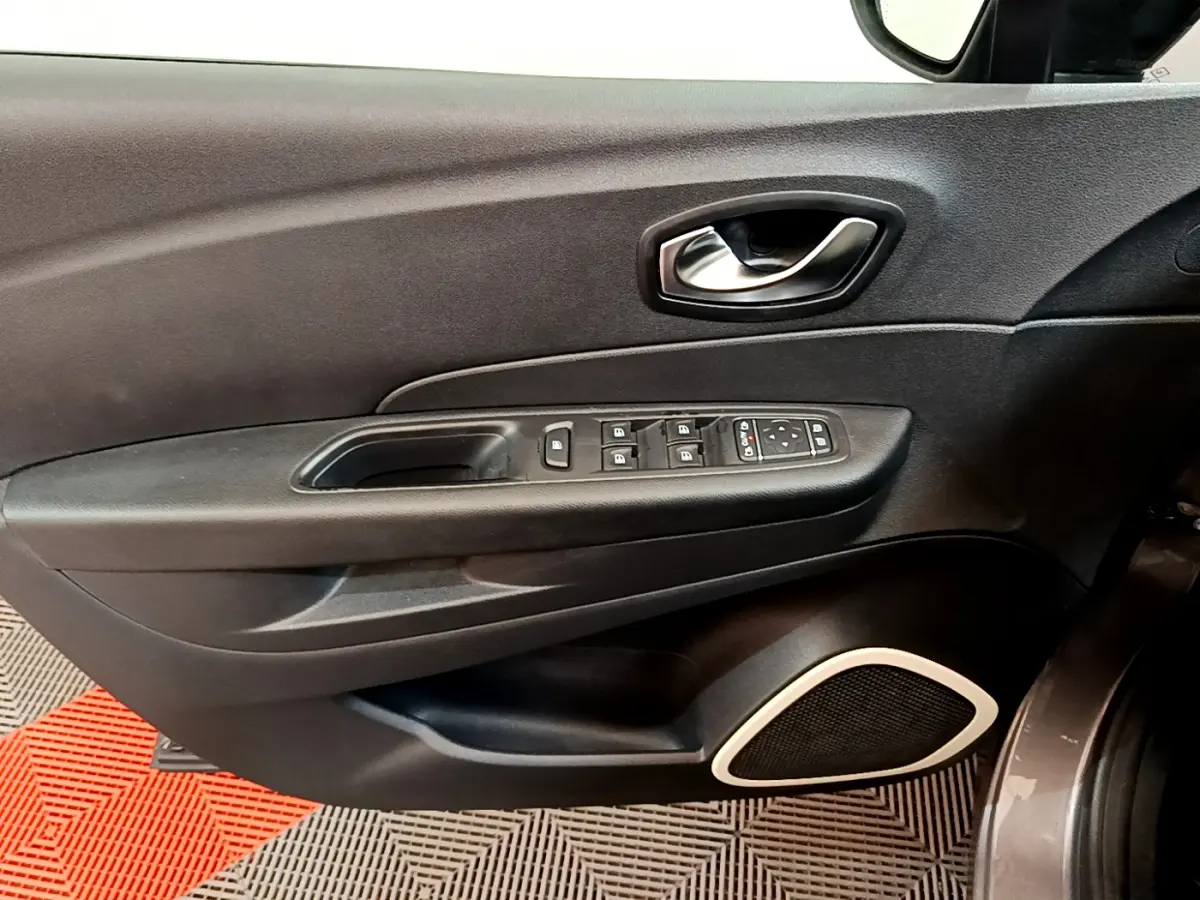 Gros plan sur la porte côté conducteur du Renault Captur gris foncé, avec commandes électriques et haut-parleur intégré.