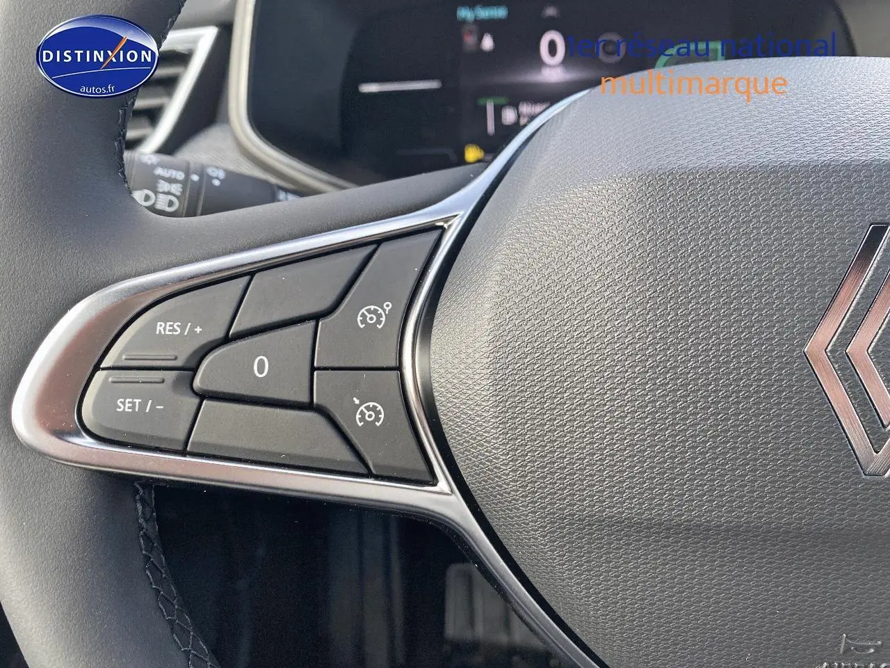 Gros plan sur le volant multifonction gris avec commandes de régulateur de vitesse et logo Renault visible.