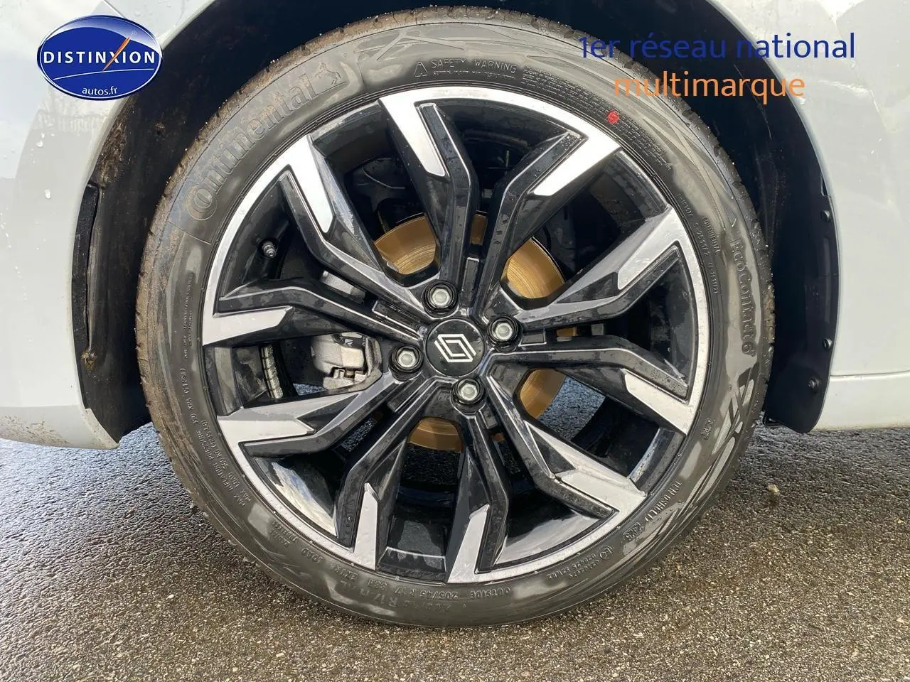 Gros plan sur la jante alu noire et argentée de la Renault Clio V gris rafale, avec logo Renault central.
