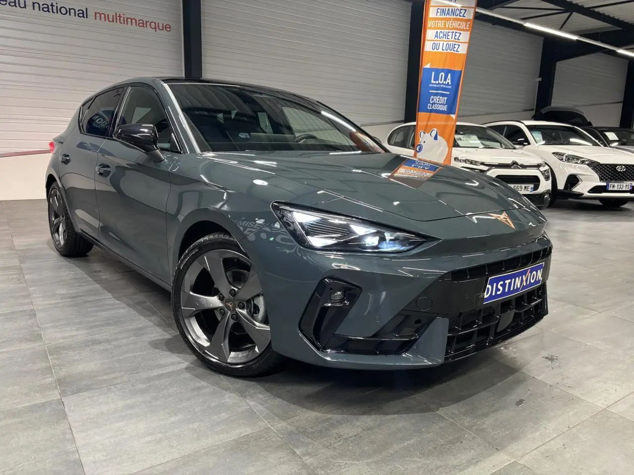 Vue 3/4 avant droite d'une CUPRA Leon bleu Fjord avec jantes anthracite et signature lumineuse Tri-LED allumée.