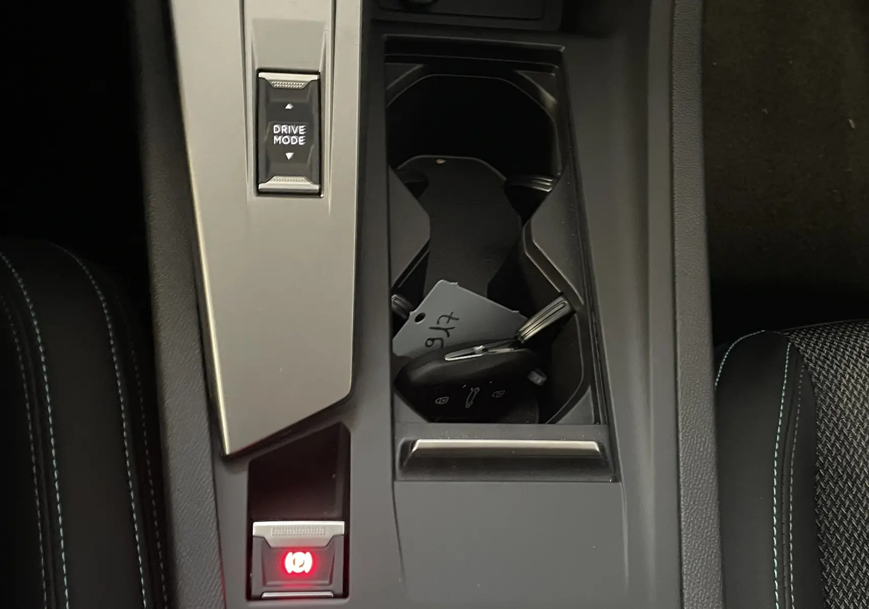 Gros plan sur la console centrale de la Peugeot 308 Hybrid 145 Allure, avec clé et bouton Drive Mode visible.