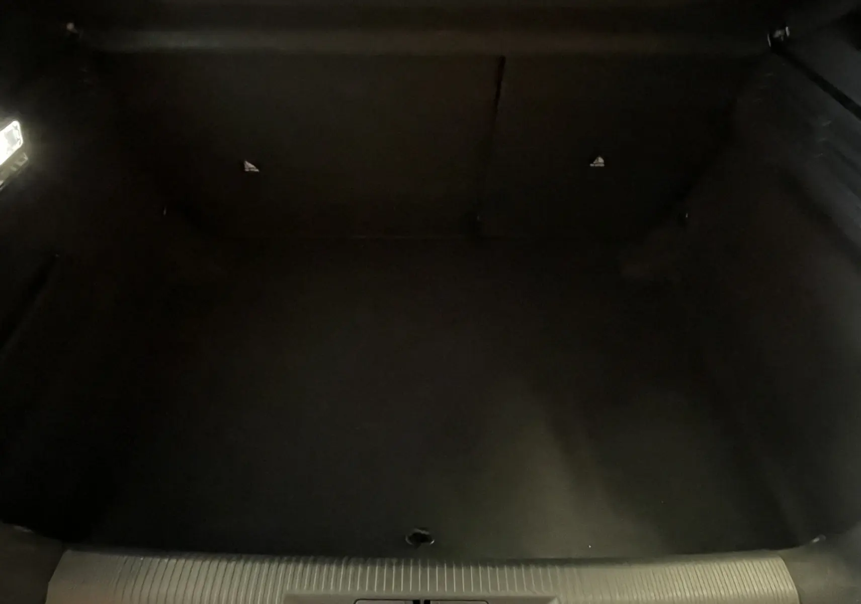 Coffre vide de Peugeot 308 Hybrid 145 e-DCS6 Allure, vue intérieure sombre sans objet visible.