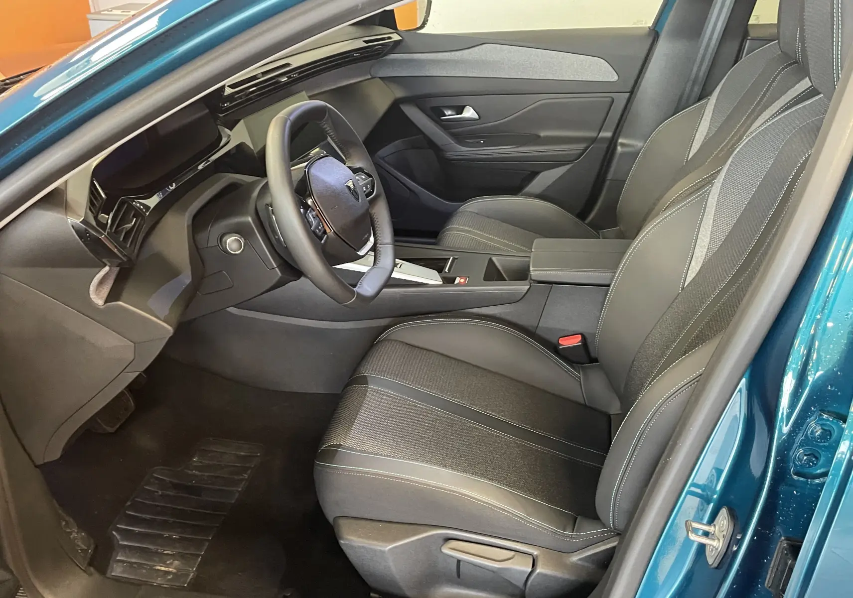 Vue intérieure côté conducteur de la Peugeot 308 Hybrid 145 Allure en Bleu Obsession, avec sièges TEP/tissu et tableau de bord moderne.