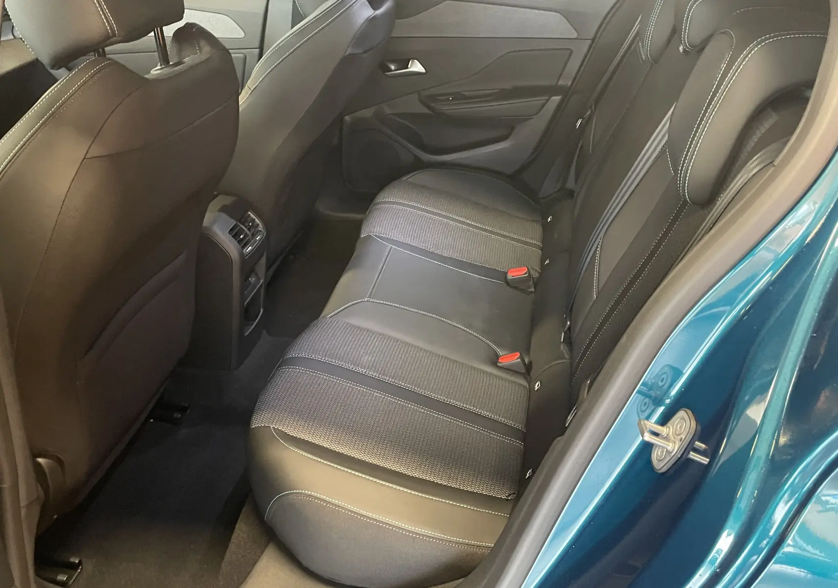 Vue intérieure arrière côté droit de la Peugeot 308 Hybrid 145 Allure bleu obsession, sièges en tissu et TEP noirs avec surpiqûres blanches.