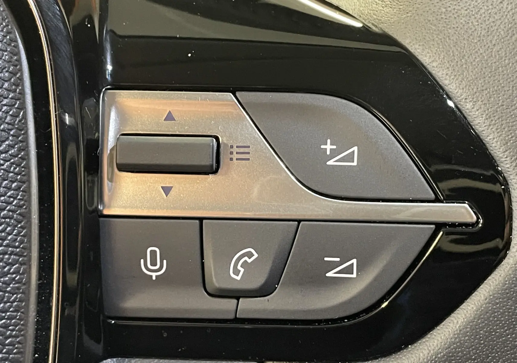 Gros plan sur les commandes multifonctions noires du volant de la Peugeot 308 Hybrid 145 e-DCS6 Allure, finition 2025.