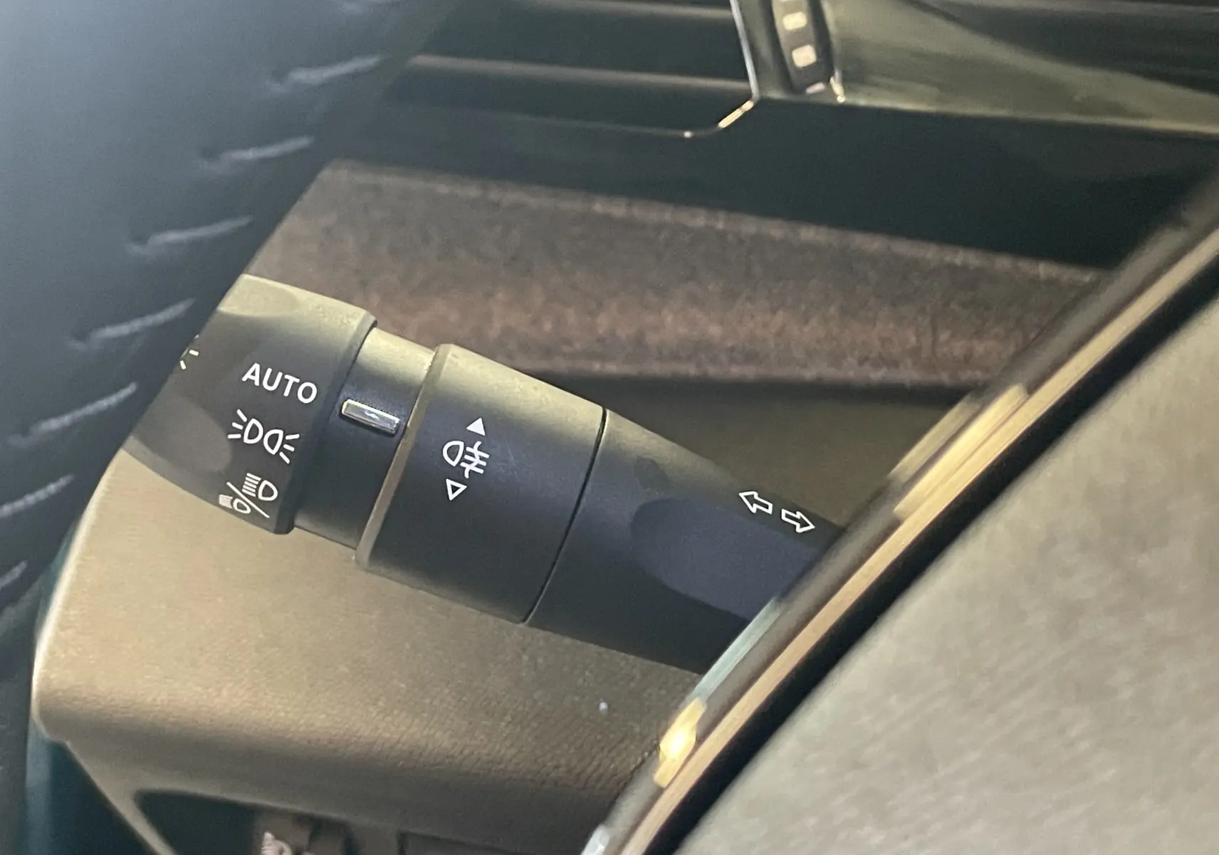 Gros plan sur la commande des feux et clignotants à gauche du volant dans l’habitacle du Peugeot 308 Hybrid 145 bleu Obsession.