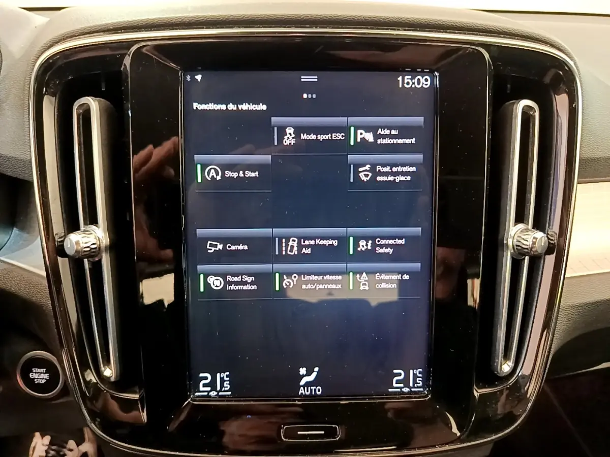 Écran tactile central noir affichant les fonctions du véhicule, entouré de la console brillante du Volvo XC40 noir.