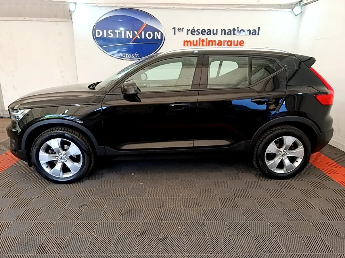 Vue de profil côté gauche d'un Volvo XC40 T2 noir 2020 dans un showroom avec sol à damier.