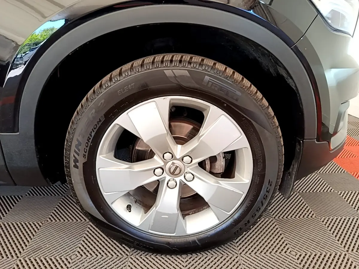 Gros plan sur la roue avant droite d’un Volvo XC40 noir, jante argentée à cinq branches, pneu hiver Pirelli.