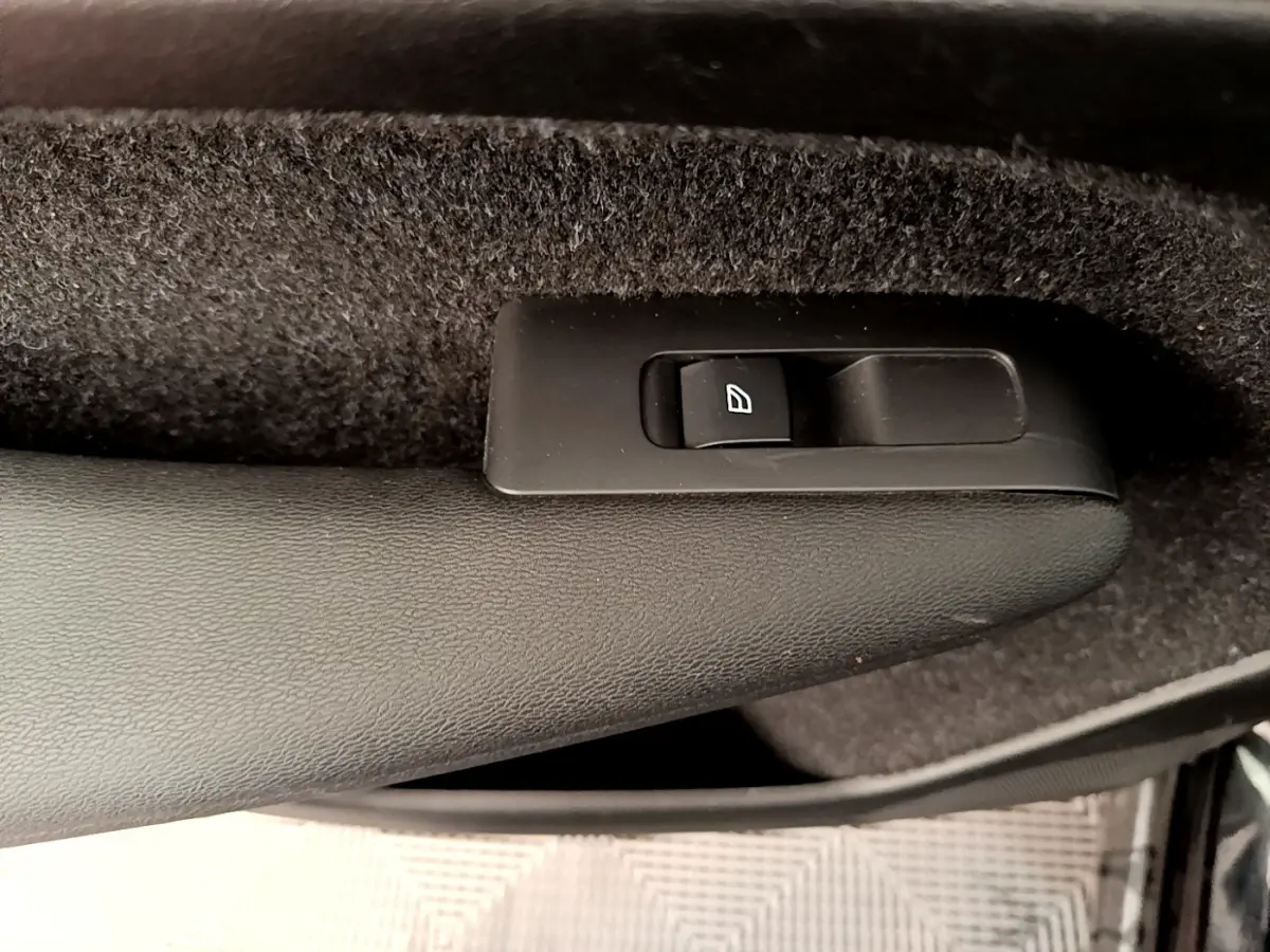 Détail du bouton de commande de lève-vitre sur la porte intérieure côté gauche d’un Volvo XC40 noir.