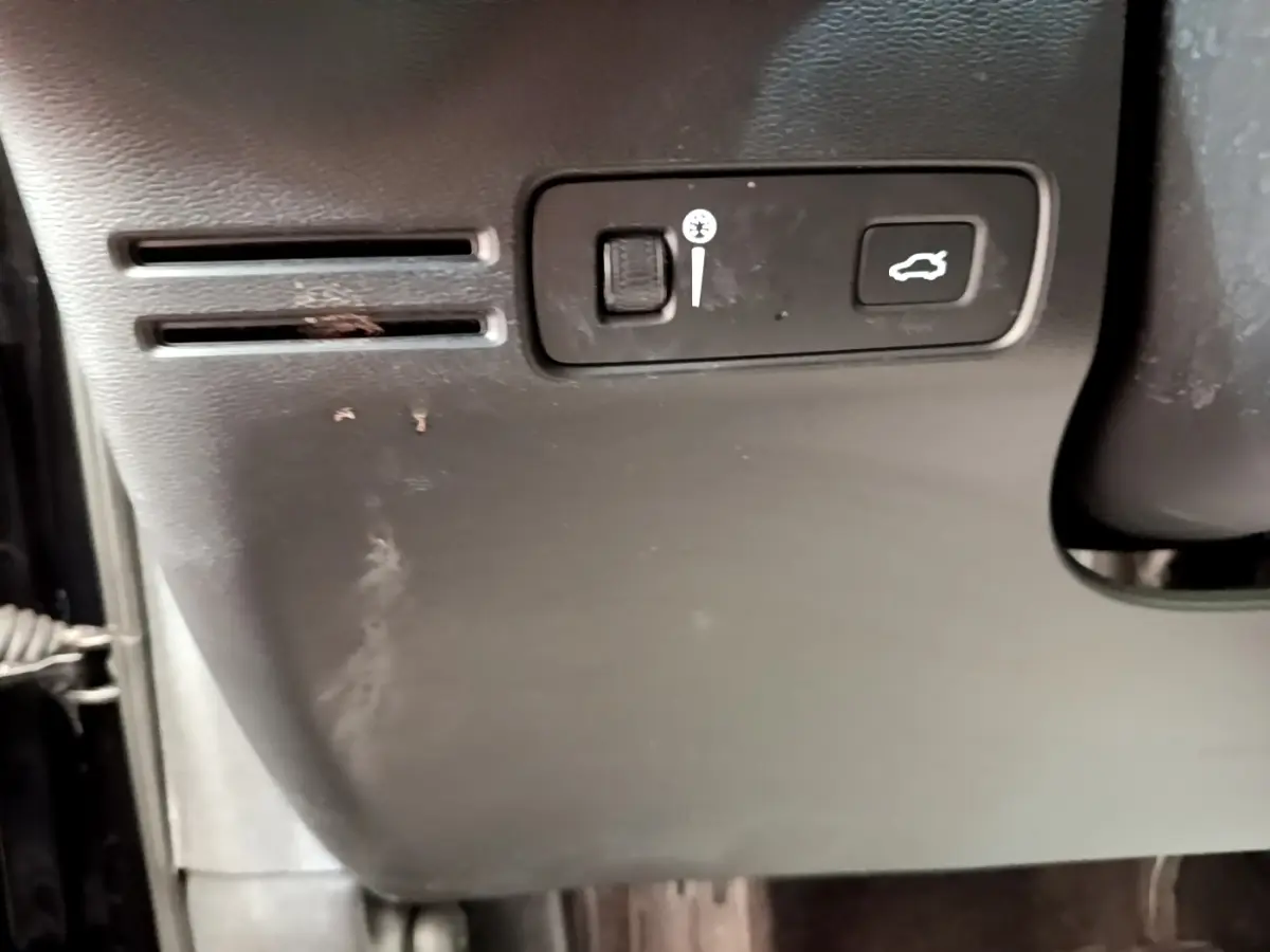 Détail intérieur montrant les commandes d'ouverture du coffre et réglage de luminosité sur un Volvo XC40 noir.