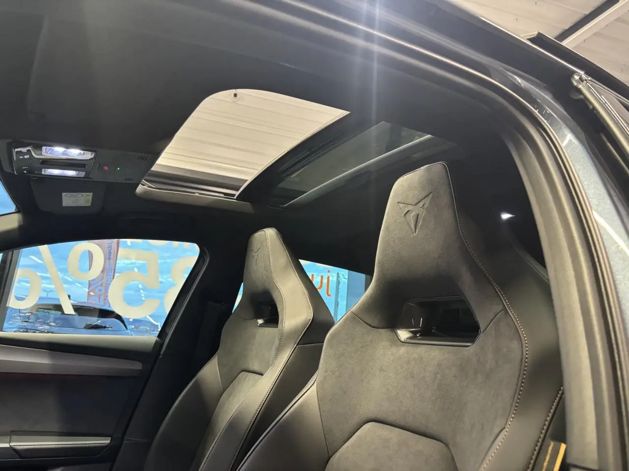 Vue intérieure côté droit des sièges baquets suédine noirs avec surpiqûres cuivrées et toit ouvrant panoramique de la CUPRA Leon gris magnetic.