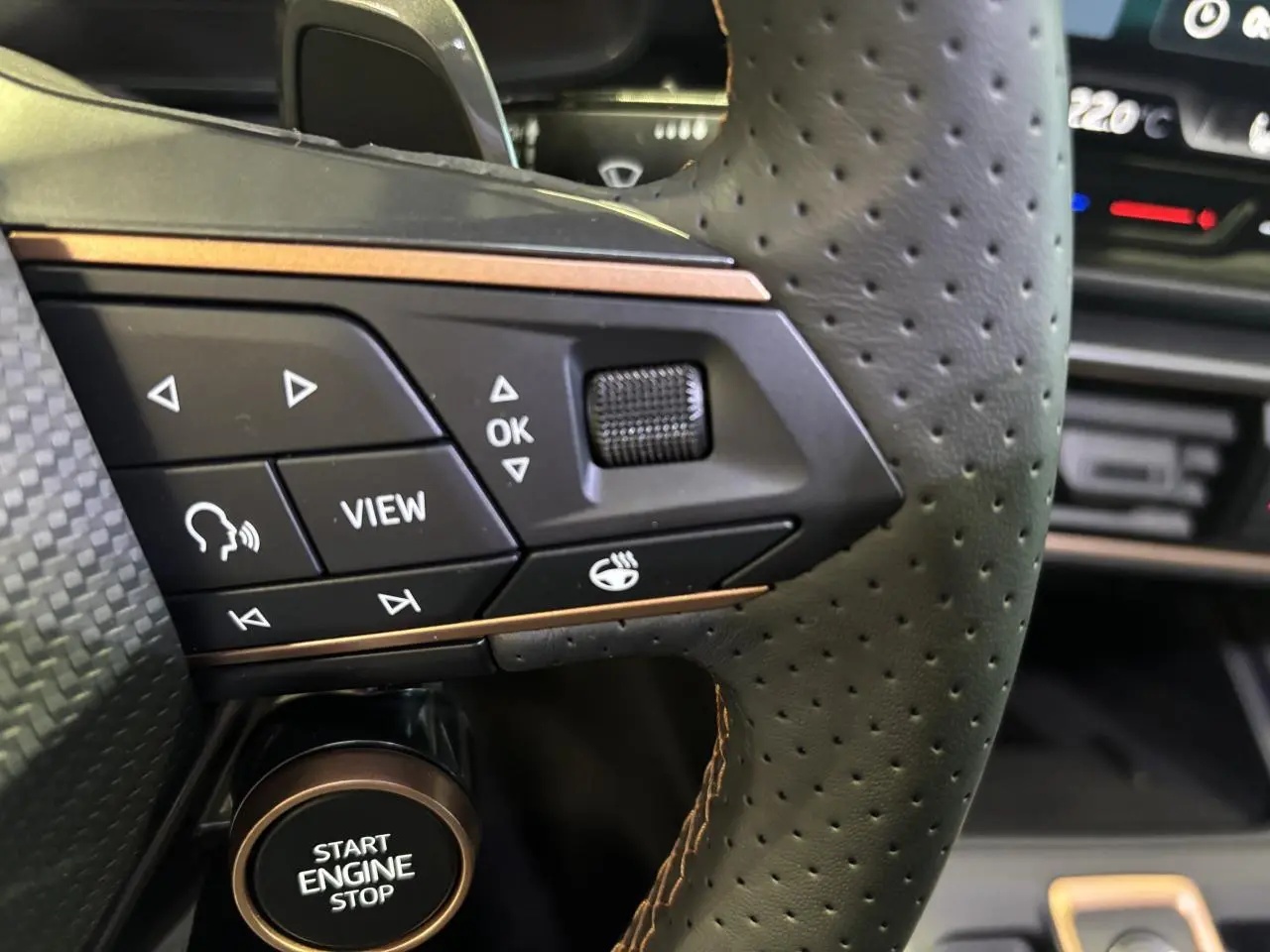 Gros plan sur le volant perforé noir avec surpiqûres cuivrées et boutons multifonctions du CUPRA Leon 2026 gris Magnetic.