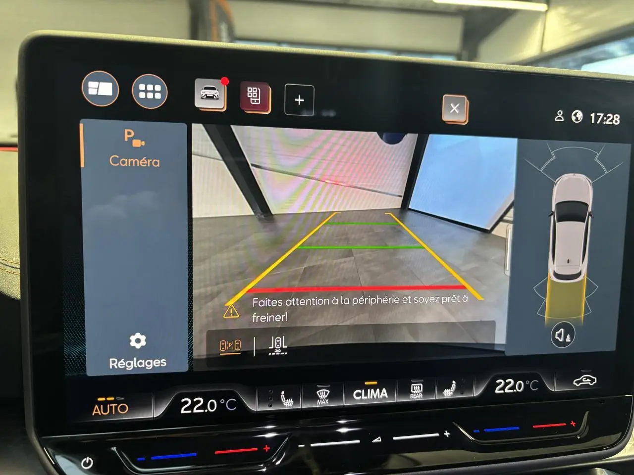 Écran tactile affichant la caméra de recul et l’aide au stationnement du CUPRA Leon gris Magnetic, vue intérieure.