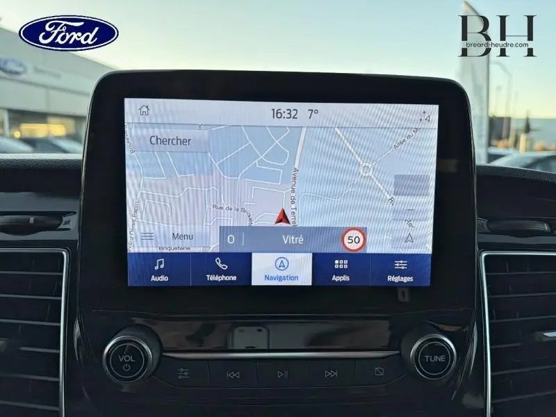 Écran tactile central du Ford Transit Custom 2023 affichant la navigation, avec commandes audio et climatisation visibles.