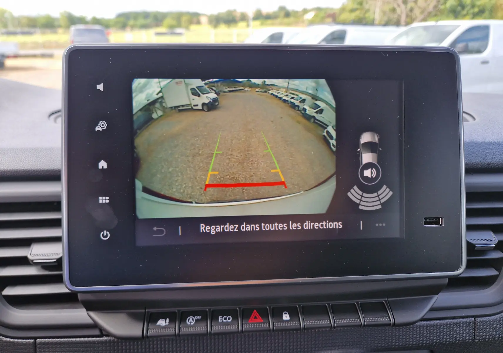 Écran tactile du Renault Trafic L2H1 blanc montrant la caméra de recul avec lignes de guidage colorées.