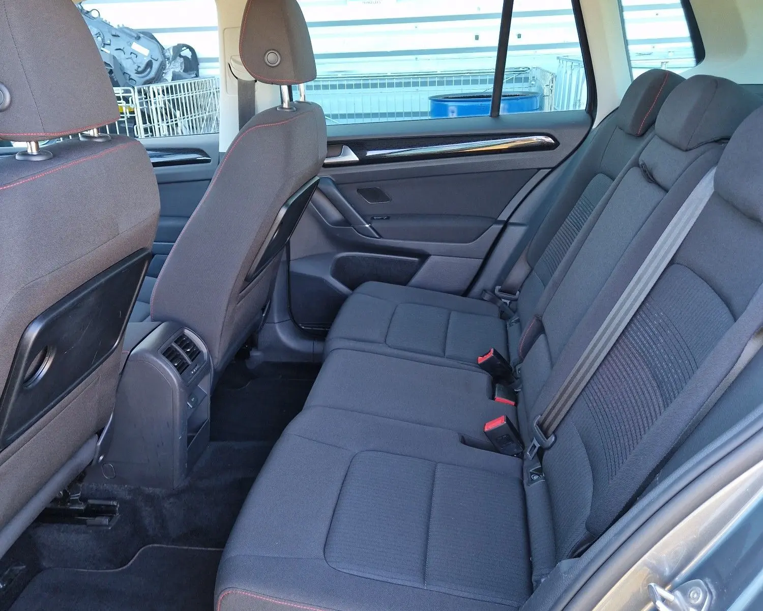 Vue intérieure côté droit des sièges arrière gris foncé avec surpiqûres rouges d'un Volkswagen Golf Sportsvan 2017 gris Indium Metal.